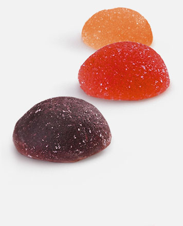 Fruit Juice Drops Una gota de zumo de fruta morada, otra roja y otra naranja colocadas una al lado de la otra.