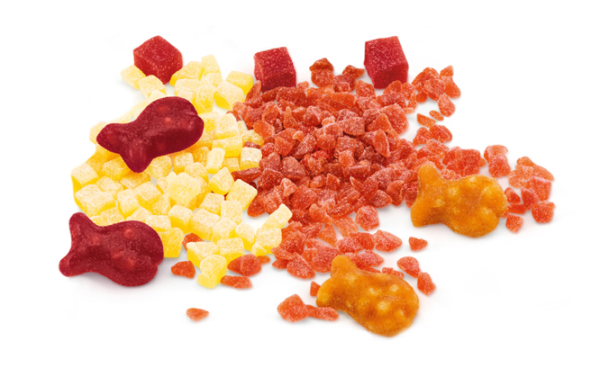 Tasty Snacks Fruchtgranulat in verschiedenen Schnittgrößen gemischt mit fischförmigen Fruchtgummis.