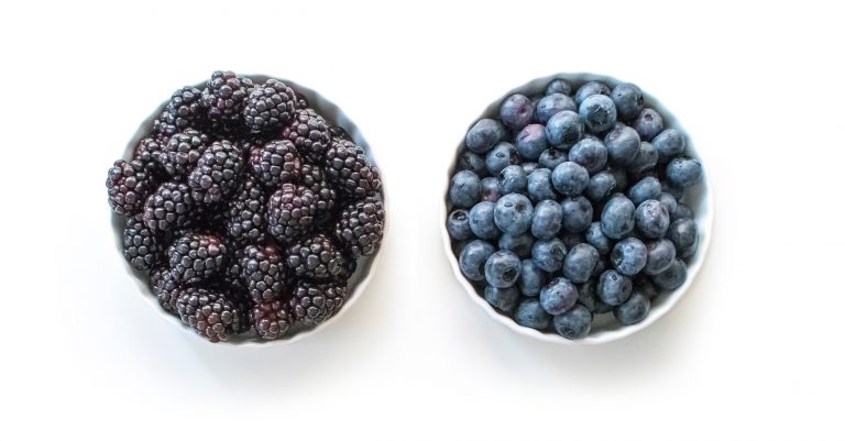 Paradise Fruits Blog Un cuenco de moras frescas junto a otro de arándanos frescos.